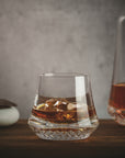 NUDE Paris whisky glass DOF, presented filled with whisky on table with grey background